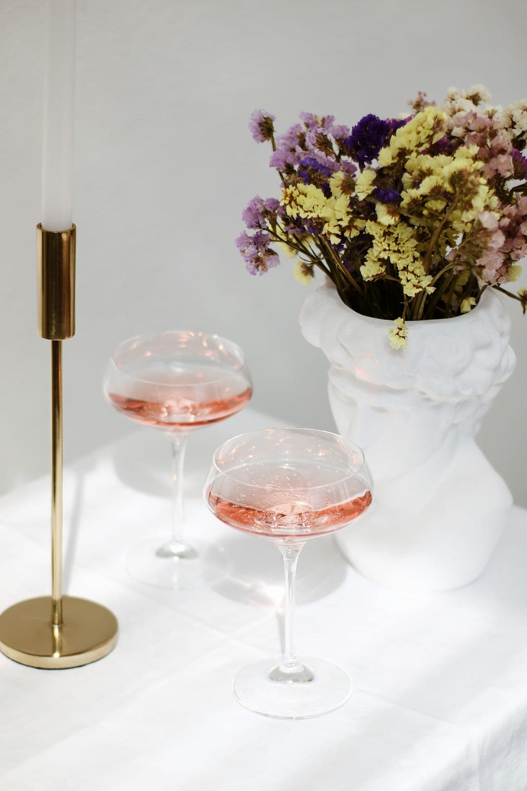 Coupes de rosé et bouquet sur nappe blanche pour une soirée after-work
